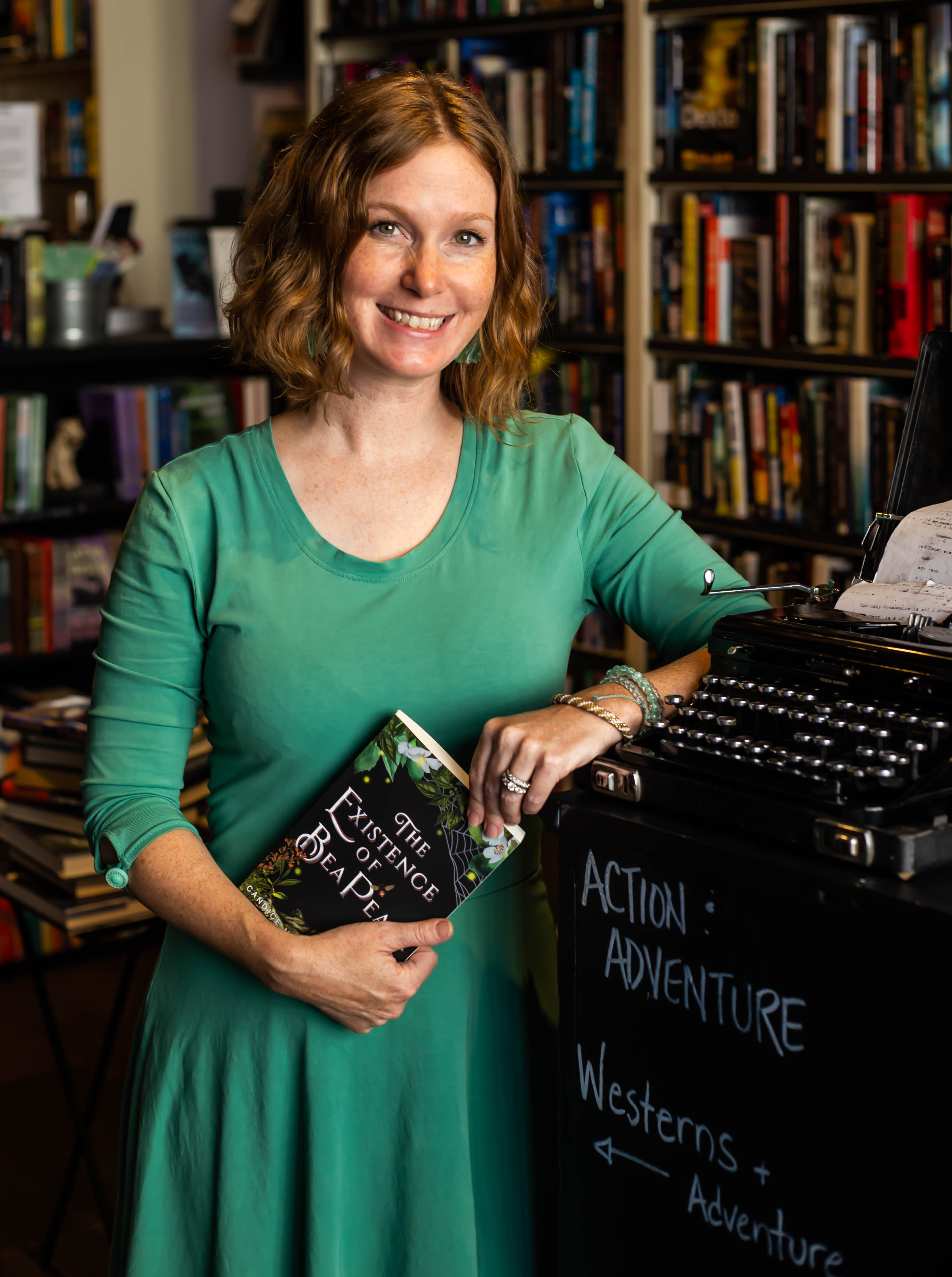 Author Candice Marley Conner stands in a bookstore holding her YA mystery The Existence of Bea Pearl.